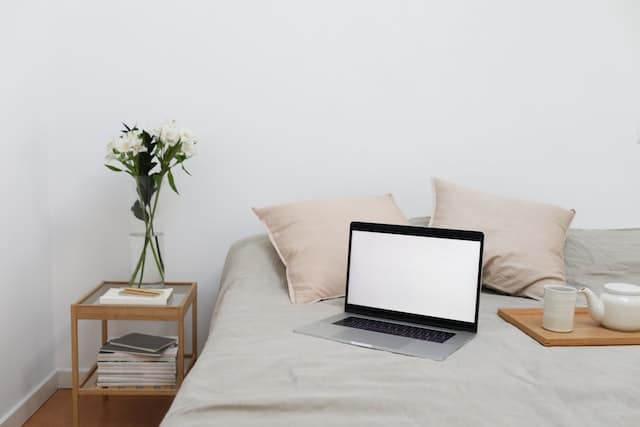 a laptop on a bed next to a tea tray
