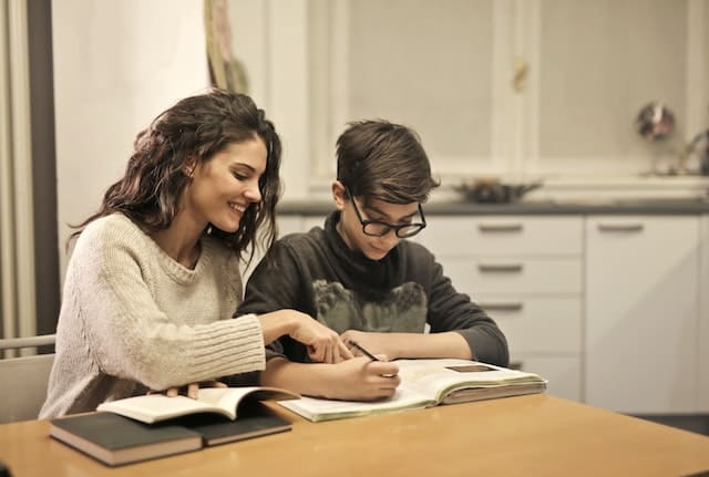 an adult helping a child do homework at a kitchen table