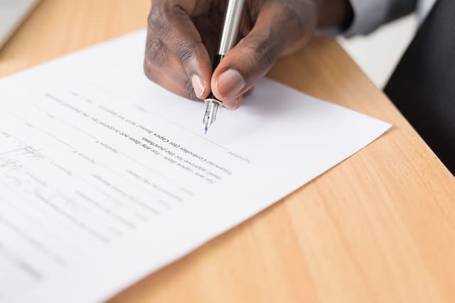 a close up on a hand signing a document