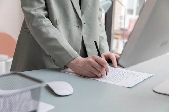 someone standing at a desk signing a paper