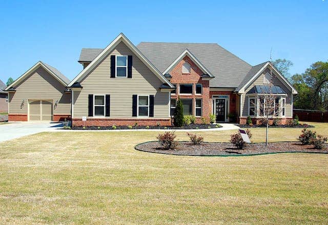 green and brick house with green front yard