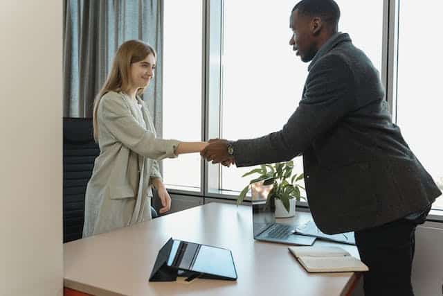 two people in suits in an office shaking hands
