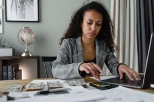 woman in suit counting cash with calculator