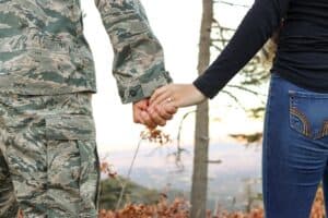 a person in a military uniform holding hands with someone in plainclothes
