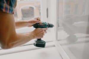 person drilling into a window pane