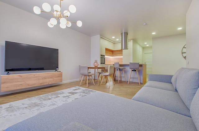 neautral-living-room-with-grey-couch-facing-flat-screen-tv-on-hard-wood-floors-covered-with-a-large-grey-rug