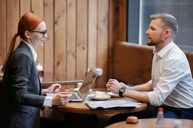 a-man-and-a-woman-having-a-business-discussion-at-a-caf-table-with-a-laptop-and-documents