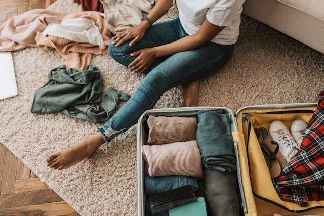 person-packing-their-suitcase-siting-on-the-floor