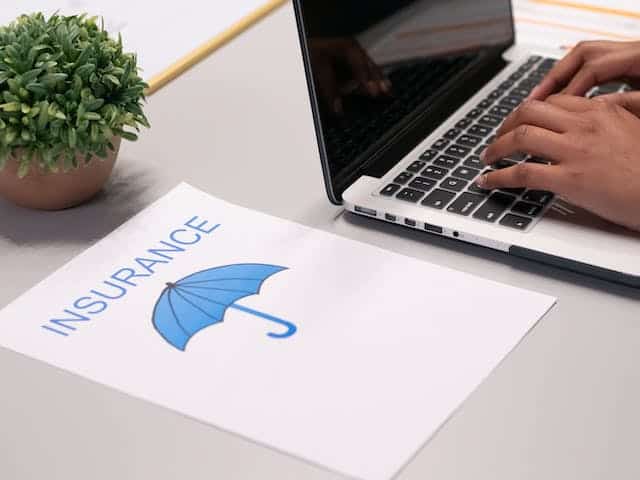 person-typing-on-computer-with-a-piece-of-paper-with-an-umbrella-on-it-with-the word-insurance-on-it