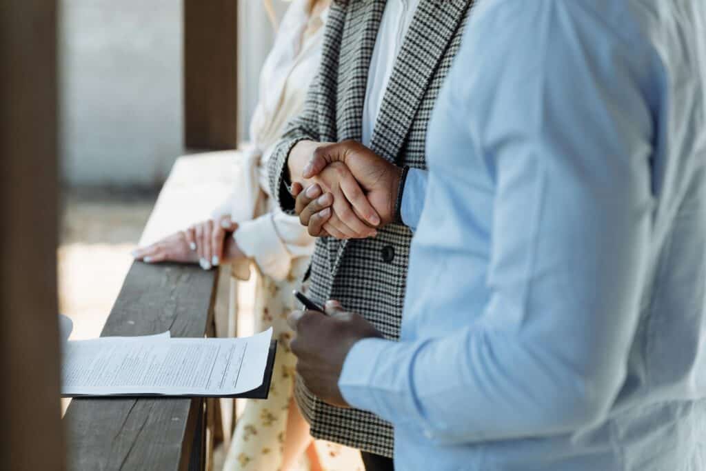 people shaking hands over a clipboard