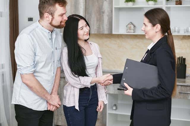 couple-shaking-hands-with-person-in-suit-holding-clipboard