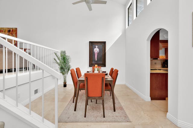 inside-home-dining-room-with-orange-chairs-and-wood-table-with-white-walls-and-stairs-to-living-room